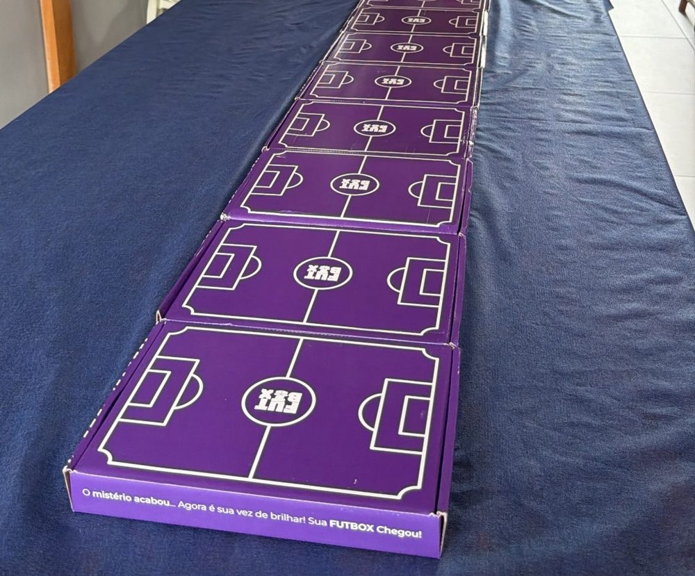 Nove caixas roxas da Futbox enfileiradas em cima da mesa