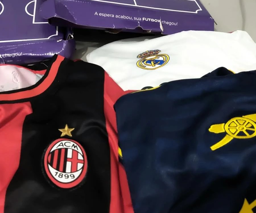 Camisas do Milan, do Real Madrid e do Arsenal ao lado das caixas roxas da Futbox